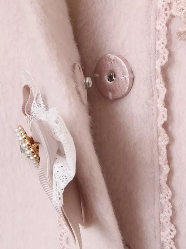Close-up of sweet lolita coat front closure showing lace trim edge round heart-shaped button and pearl bow accent side view