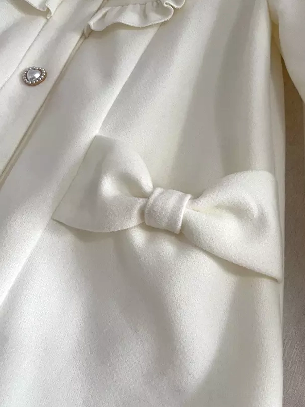 Close-up top-down view of lolita coat front placket detail showing pearl front buttons, fabric bow trim, and ruffled front trim decoration