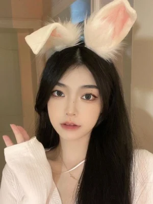 Cream white faux fur rabbit ear headband worn by girl with long black hair, frontal close-up showcasing Sweet Lolita rococo style headwear with pink inner ear details, soft plush texture and adorable kawaii design