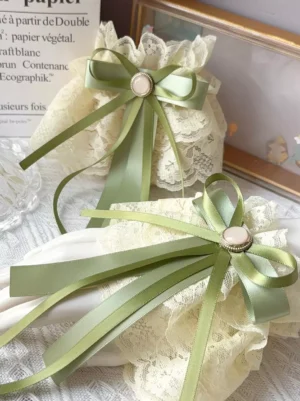 Sweet lolita cream yellow ruffled lace oversleeves with matcha green satin bow and round gem buckle, styled on tabletop with decorative stationery and vintage frame
