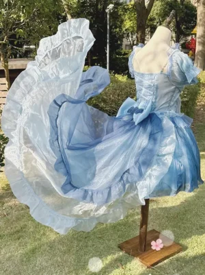 Gradient blue Sweet Lolita detachable train accessory with ruffled organza hem and puff sleeve detail on navy lolita dress rear quarter view outdoor lawn