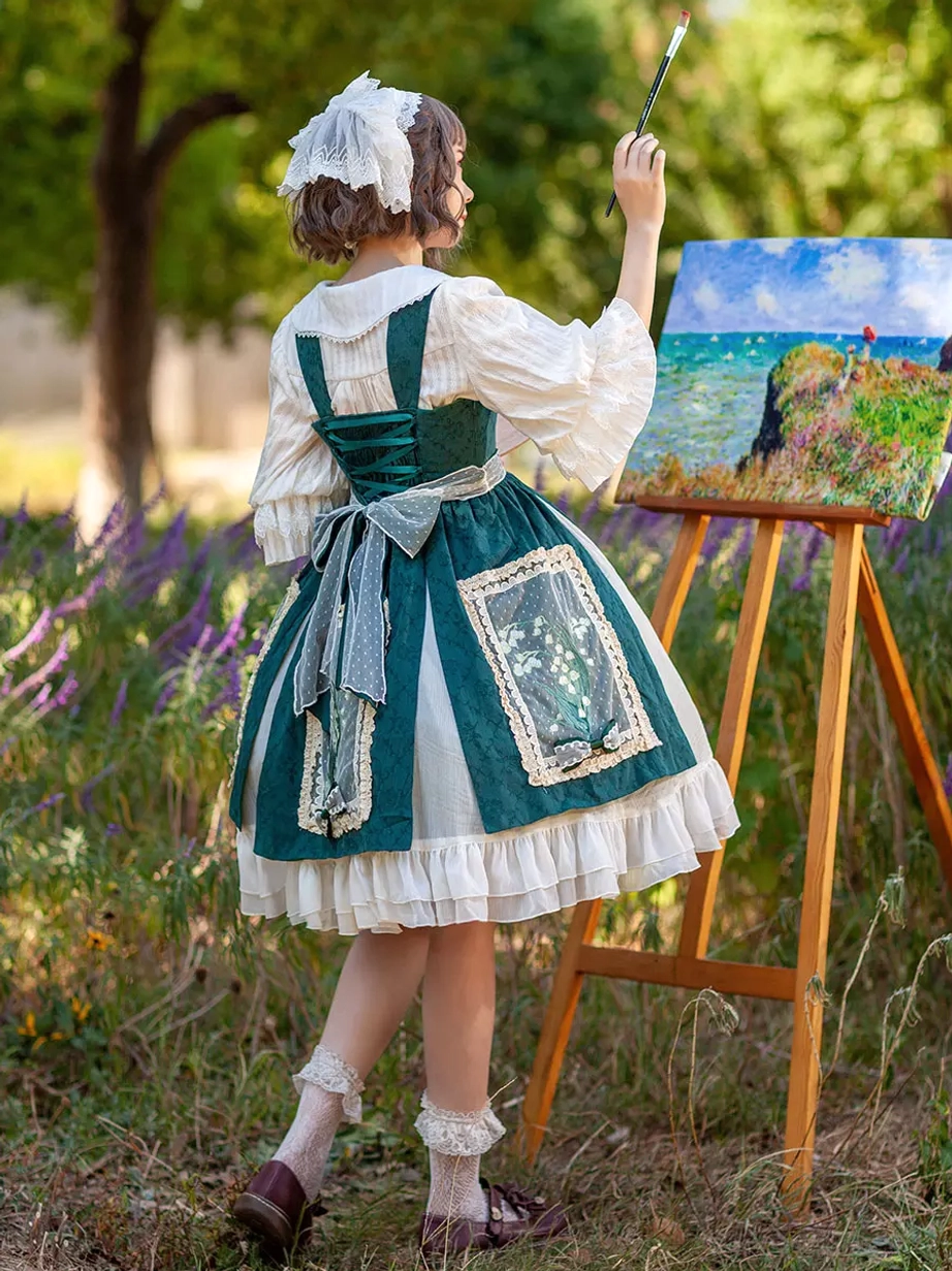 Back full view of sage lolita dress revealing cross back straps, large decorative bow, and embroidered front panels