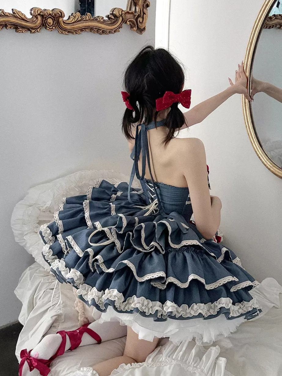 Back view of sweet lolita dress showing halter tie ruffled layered skirt and red hair bows on seated model