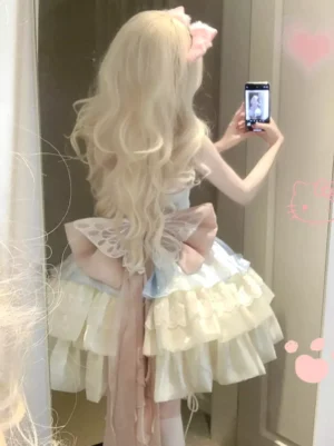 Back mirror view of sweet lolita dress showing large back bow, layered ruffled skirt, pastel color blocking and fairy aesthetic on blonde long-haired model