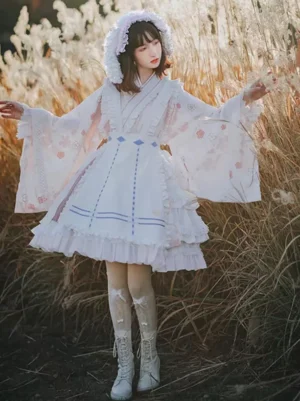 Sweet lolita kimono-style dress with cherry blossom pattern, blue decorative trim, wide bell sleeves, layered ruffled hem, fuzzy bonnet, white tall boots, outdoor reed field, full front view