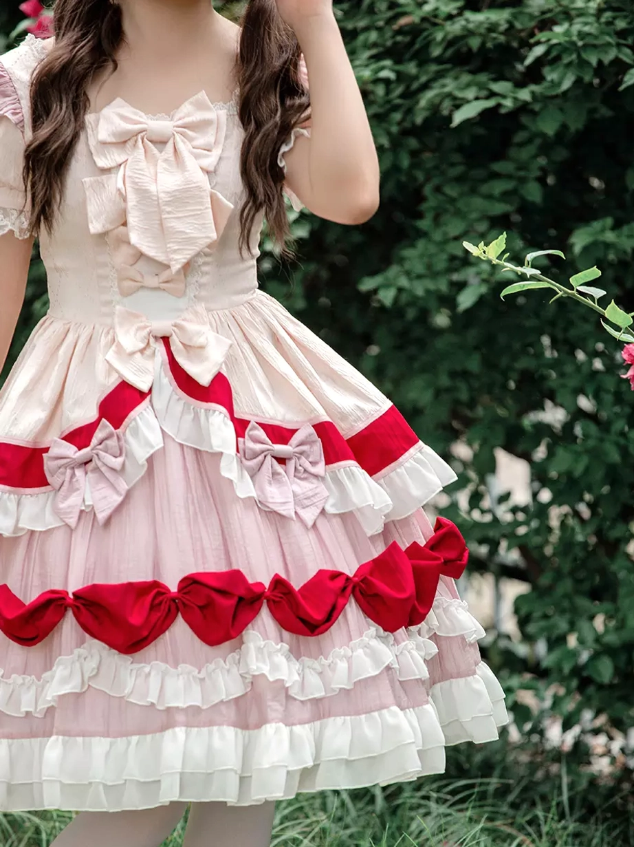 Close-up detail view of Sweet Lolita dress front showing square neck with large front bow, dual-color bow trims on skirt, and cream and light pink fabric texture