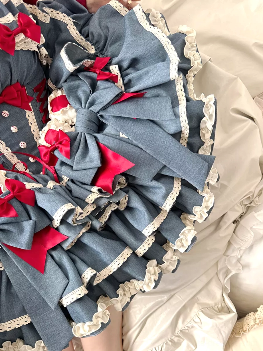 Overhead flat lay of blue sweet lolita dress multi-layer ruffled skirt with red bows fabric flowers and white lace trim
