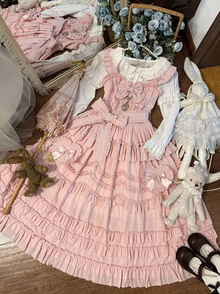 Pink lolita dress set displayed flat lay overhead with stuffed toys, Mary Jane shoes, lace-trimmed collar and tiered ruffles on wooden floor