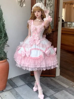 Sweet Lolita dress in classic pink with layered ruffled skirt, silk bows at bust, and delicate lace trim, front three-quarter view worn by model with curly blonde hair and matching accessories