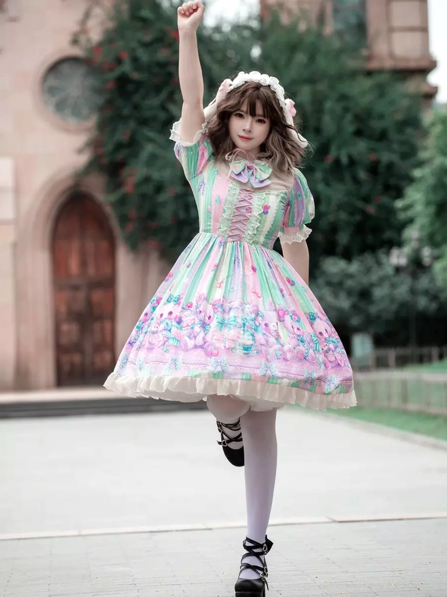 Sweet lolita dress front view with one leg lifted pose, displaying ruffled short puff sleeves, high waist construction, ruffled dress hem detail, and cartoon floral print