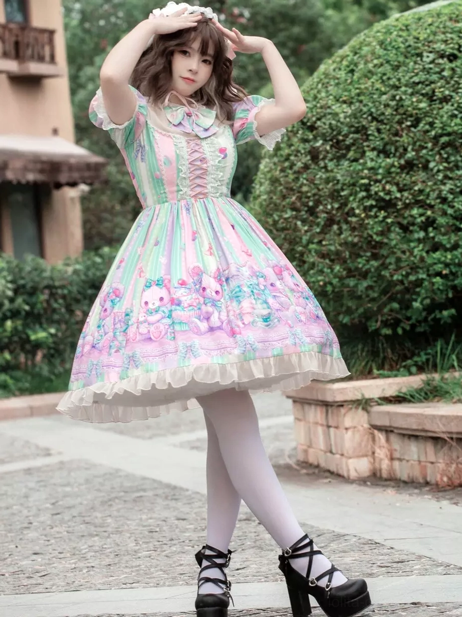 Sweet lolita dress front three-quarter view with hands-on-head pose showing ruffled short sleeves, neck bow detail, black platform heels, and complete outfit styling with bunny accessories