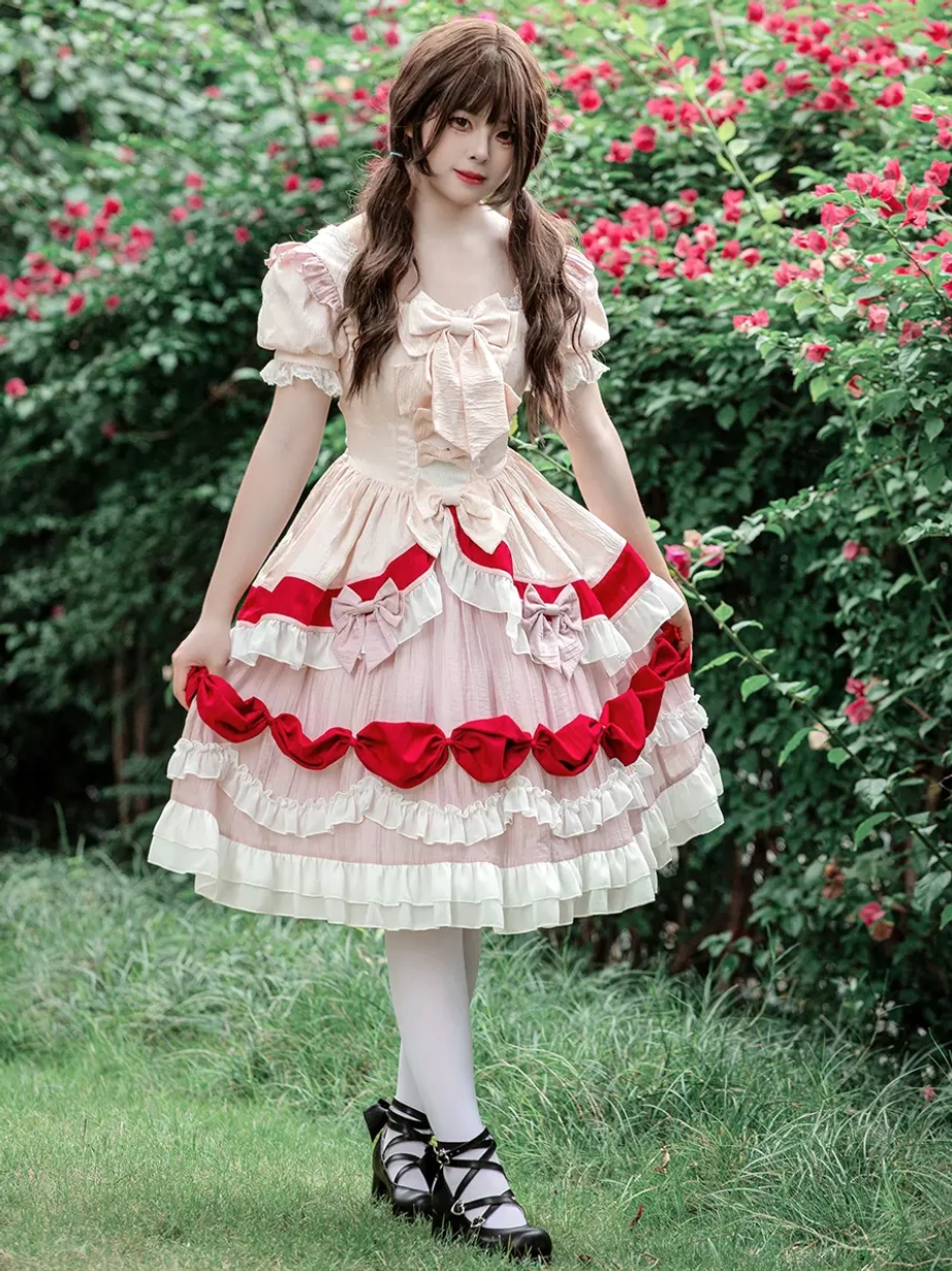 Sweet Lolita OP dress side profile view of model standing on lawn wearing white stockings and black lolita shoes with layered ruffled skirt and bow decorations