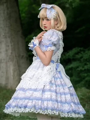 sweet lolita dress side three-quarter perspective in woodland setting, featuring puff sleeves, white lace apron front, and striped printed skirt trim with blue coordinating hair bow accessory