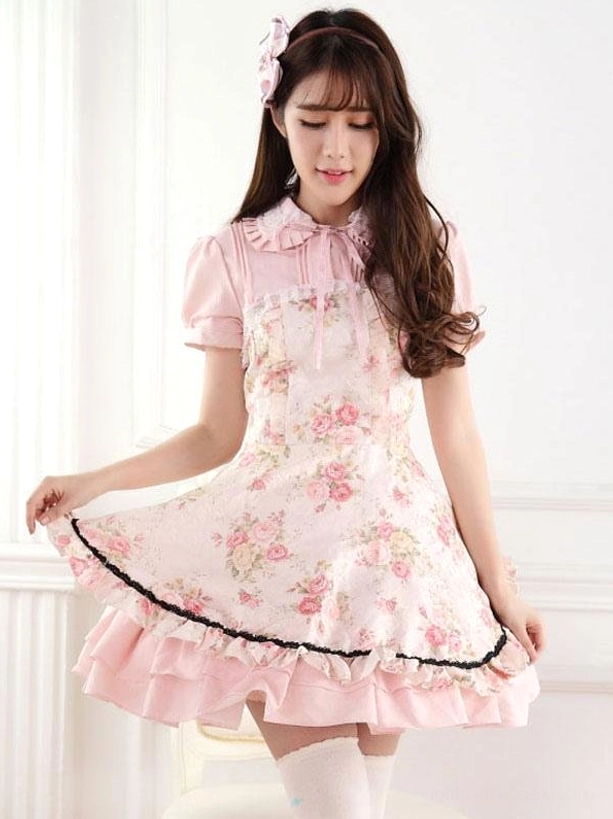 Lolita dress front side view detail showing short puff sleeves with ruffles, lace hem trim in black, white thigh-high stockings, soft rose floral print on pink base fabric, dress hem movement