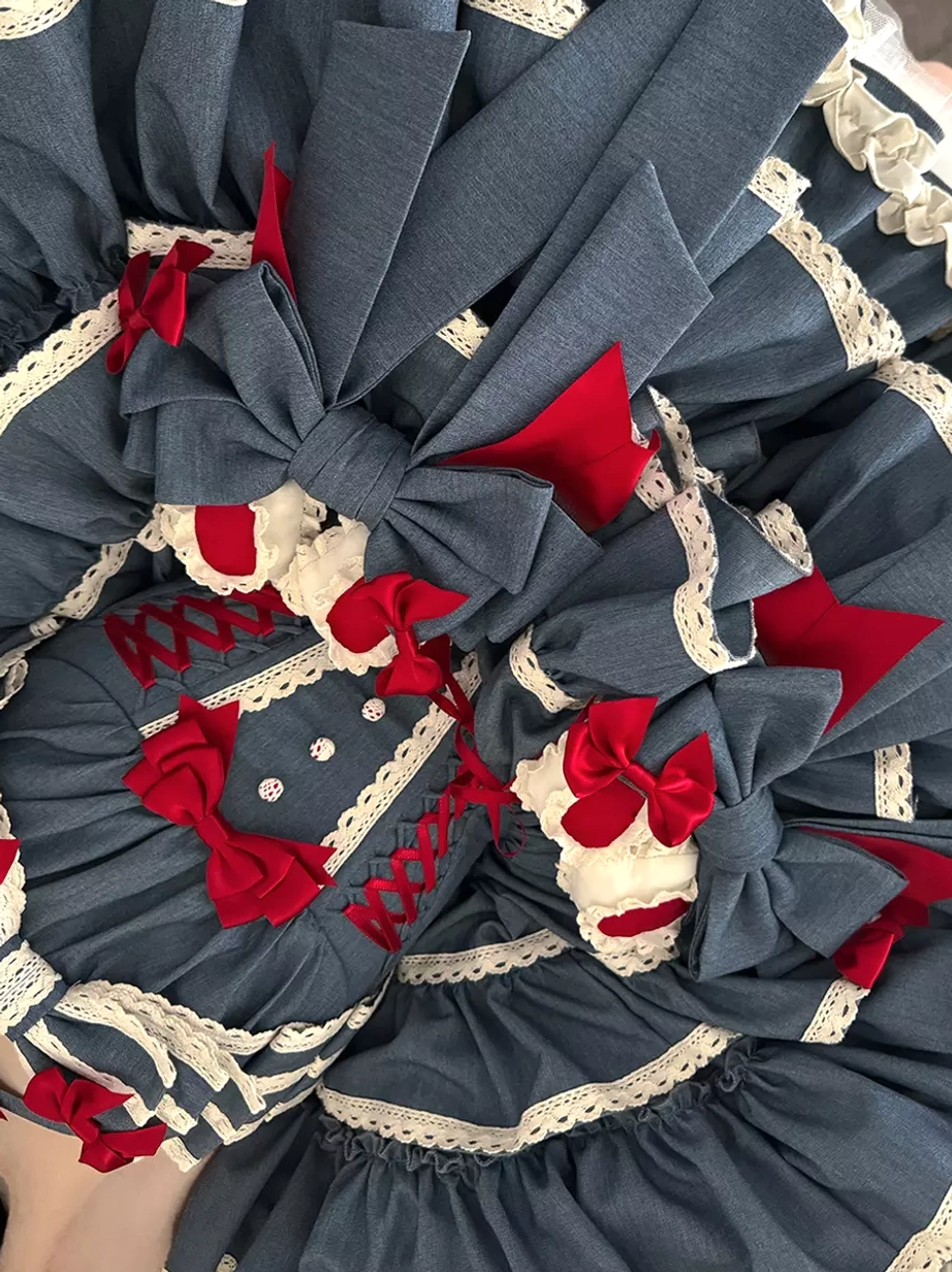 Overhead close-up of blue sweet lolita dress skirt showing red bows white lace trim fabric flowers and denim-blue textile