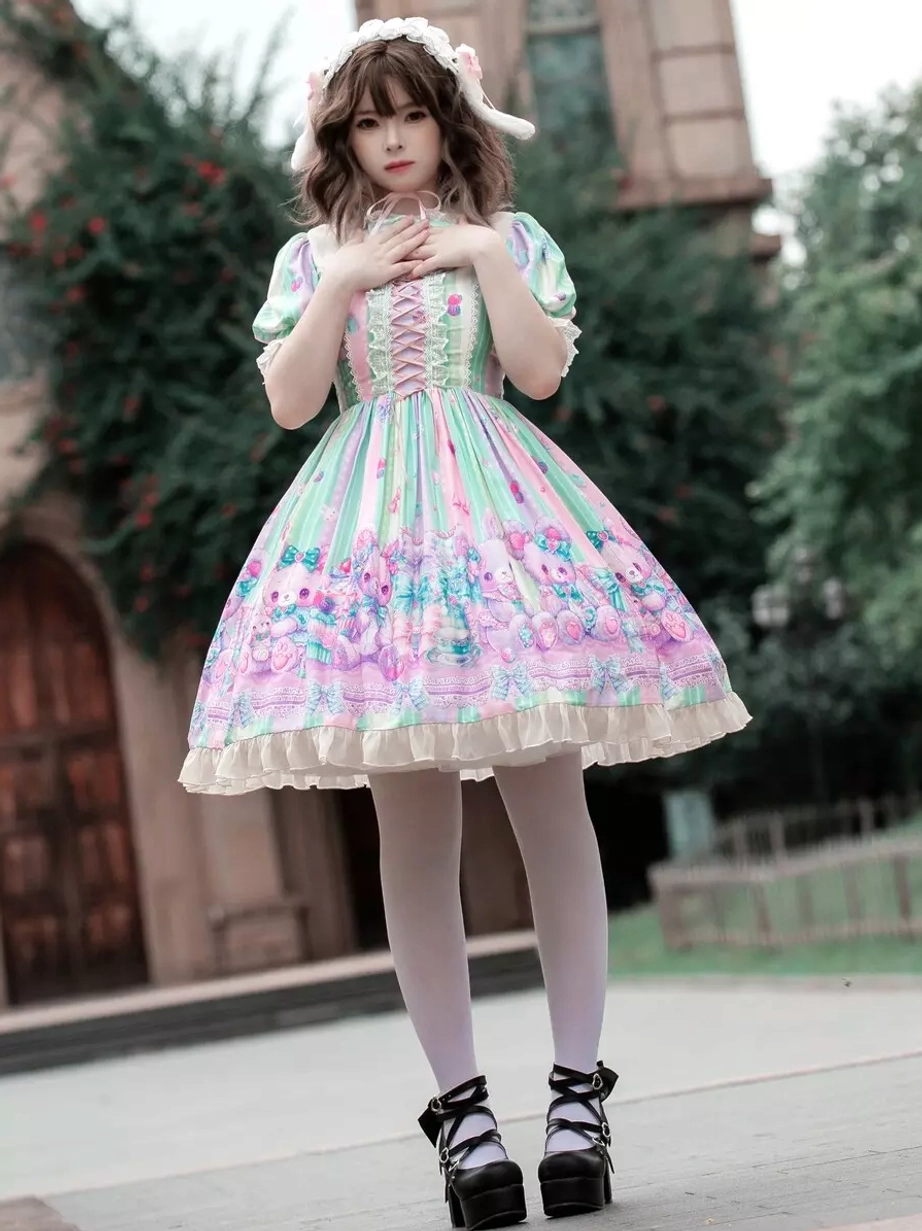 Sweet lolita dress full front view with hands-on-chest pose, vertical stripe pattern detail, lace-up bodice front closure, and coordinating ruffled neckline with bunny hair accessory