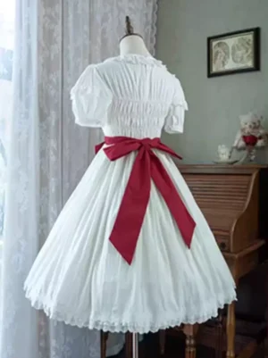 Back view of white sweet lolita dress showing shirred bodice and large red waist bow, ruffled hem lace trim detail