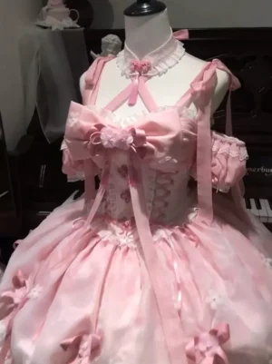 Pink sweet lolita fairy dress close-up front view showing heart-shaped lace choker neckline, corset bodice with cross-strap ribbons, 3D floral bust bow on dress form