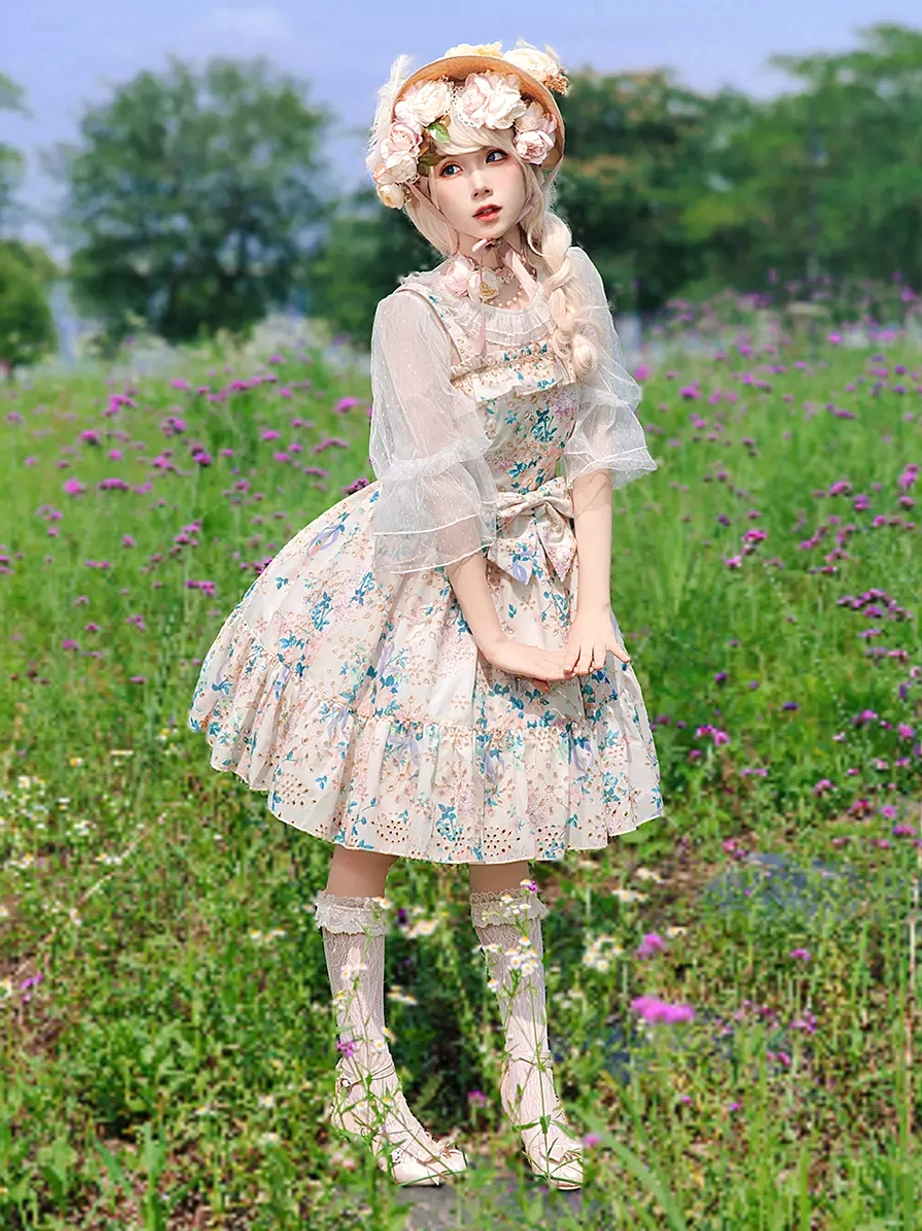 Model wearing light pink sweet Lolita floral dress outdoors in flower field side front full-body view with sheer bolero flower hat ruffled socks styling