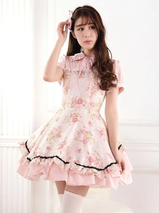 Sweet lolita one-piece dress front full-body view featuring pink rose floral print, ruffled Peter Pan collar, short puff sleeves, black lace-trimmed ruffled hem, white thigh-high socks, studio photography