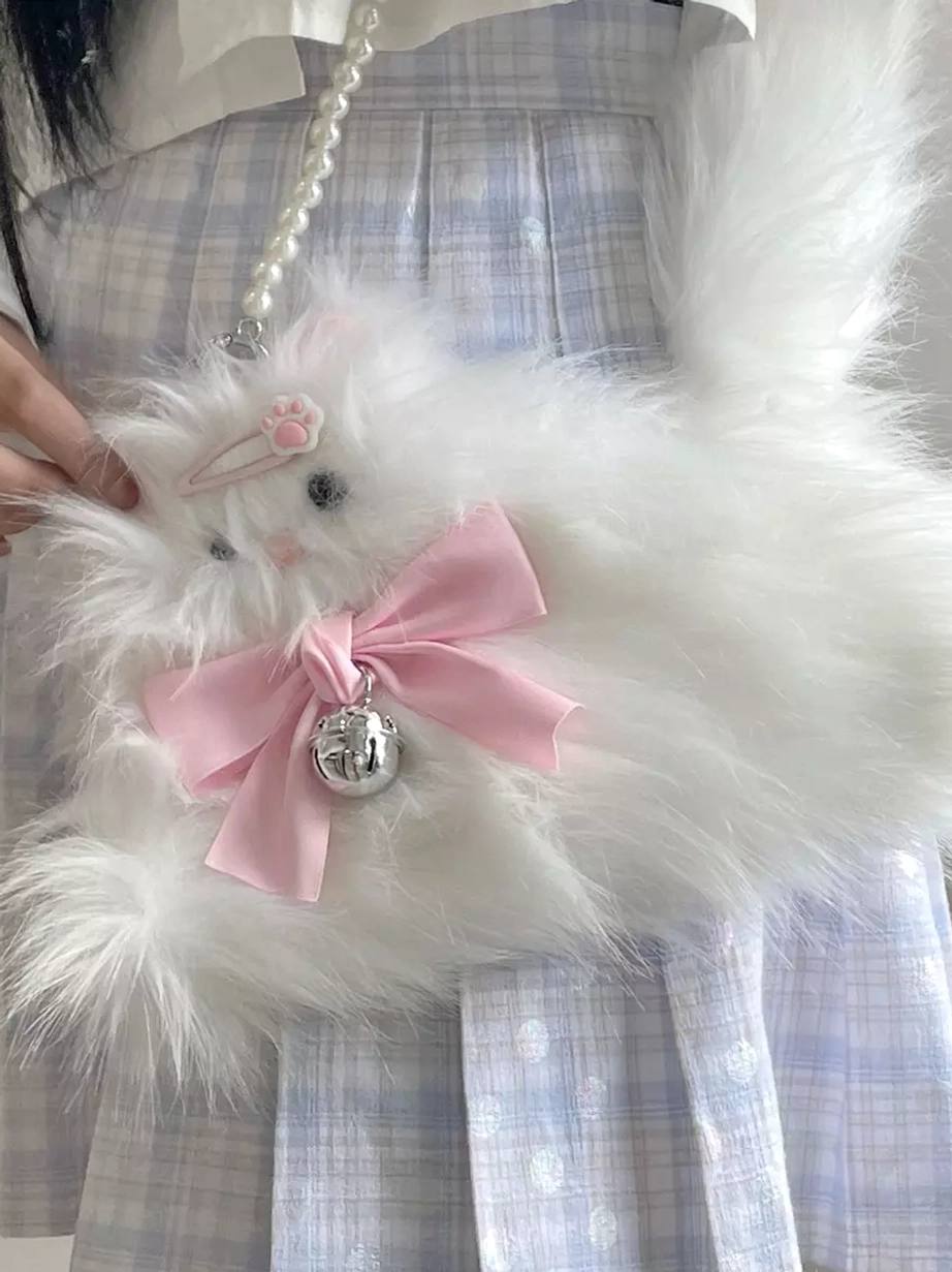Sweet Lolita fluffy white cat crossbody bag with pink bow and silver bell worn with plaid JK skirt, close-up lifestyle shot featuring pink hair clip coordination