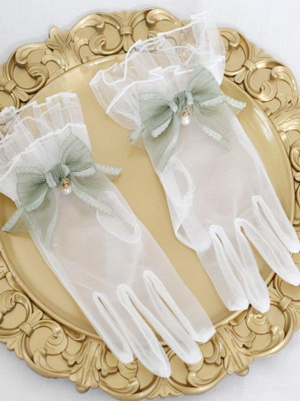 Sage green pearl bow sheer mesh lolita gloves with ruffled cuffs displayed on ornate gold tray