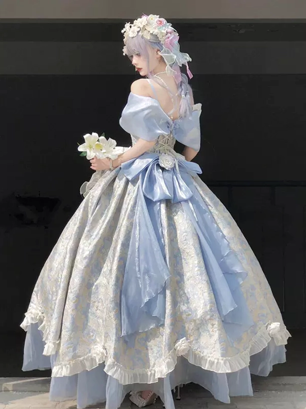 Back three-quarter view of off-shoulder sweet lolita ball gown featuring large blue back bow, blue underlayer skirt, and full princess silhouette with flower crown accessory in studio