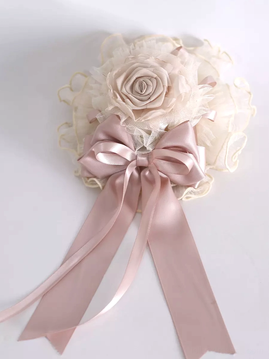 Flat lay top-down view of sweet lolita headdress featuring large dusty pink satin bow ivory ruffled tulle flower decor and lace trim detail
