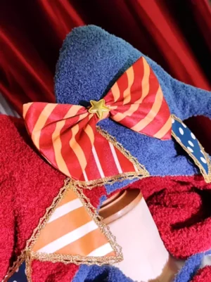 Close-up overhead view of sweet Lolita headdress showing gold star charm, polka dot patchwork, striped bow, and gold-trimmed pennant decorations