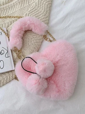 Sweet Lolita heart-shaped crossbody bag in soft pink faux fur with dual pom-pom charms and gold chain strap displayed in flat lay on white linen