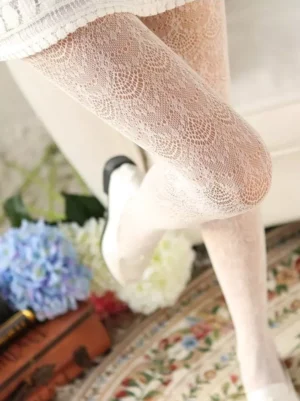 Close-up detail of delicate off-white jacquard lace tights showing intricate circular floral weave pattern on vintage carpet background, sweet lolita pantyhose texture