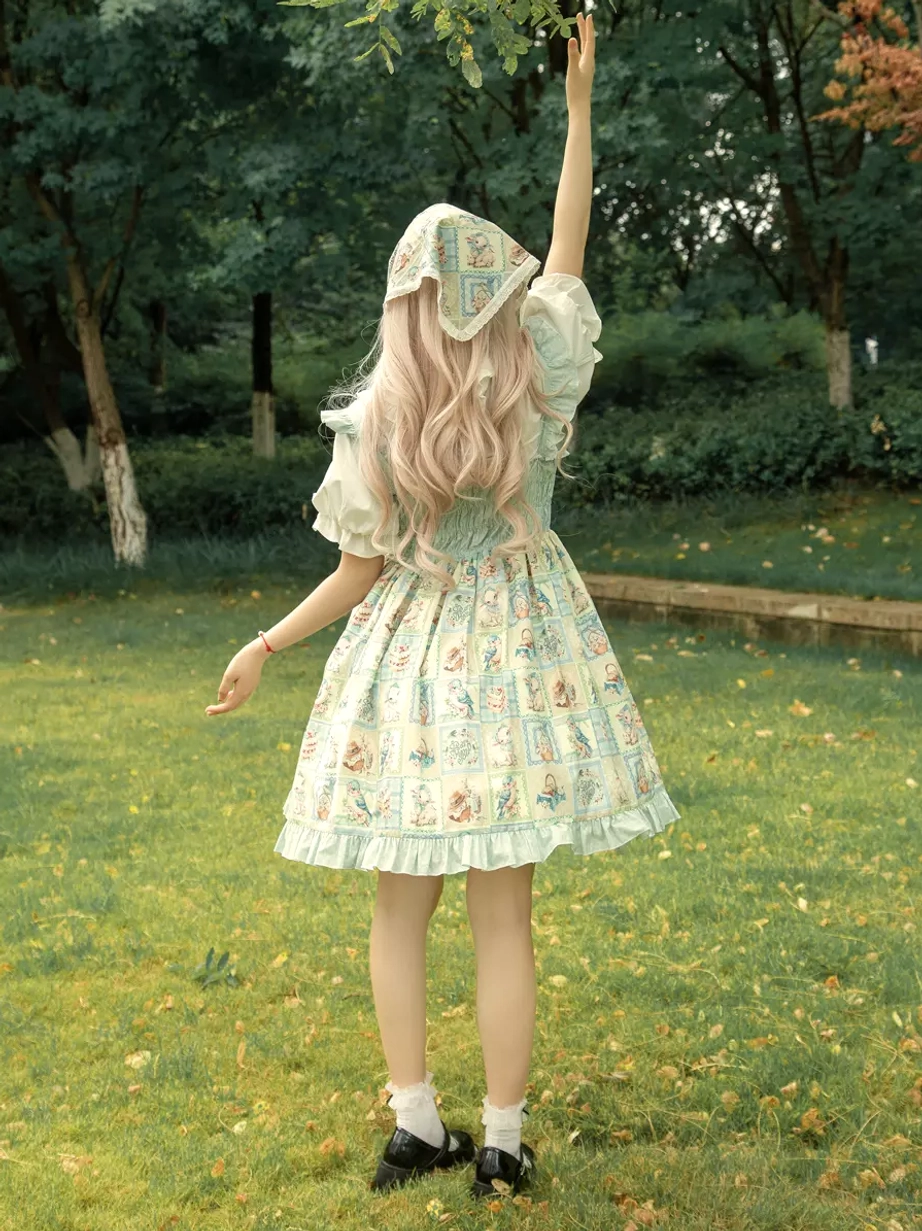Back full body shot of sweet lolita JSK dress showing long skirt drape, flared printed design, matching printed headscarf, waist bow decoration, and blonde hair coordination