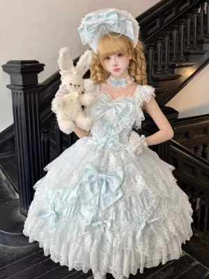 Light sky blue sweet lolita JSK dress full front view with spaghetti straps, large satin bow, and tiered lace ruffles on vintage stairwell with blonde model