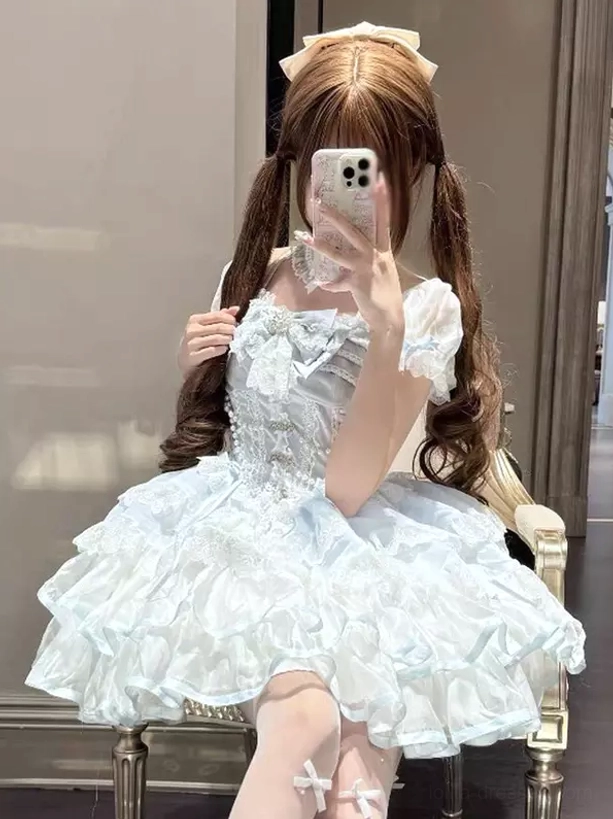 Sweet lolita dress seated front view showing multi-tier ruffle skirt silhouette with lace-trimmed corset bodice on model wearing coordinated stockings