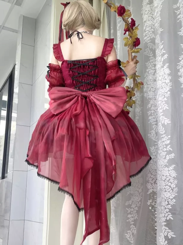 Burgundy lolita JSK dress back view on model displaying oversized back bow, lace-up back closure, flower garland accessory prop indoor setting