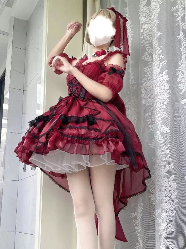 Burgundy sweet lolita JSK dress front view on model with off-shoulder sleeves, corset waist, high-low tulle skirt, matching hair ribbon indoor