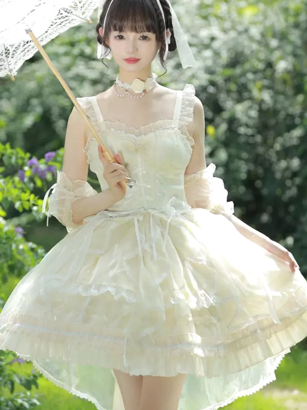 Ivory lolita JSK dress with ruffled straps, matching arm cuffs, and lace parasol prop worn by model in outdoor garden setting