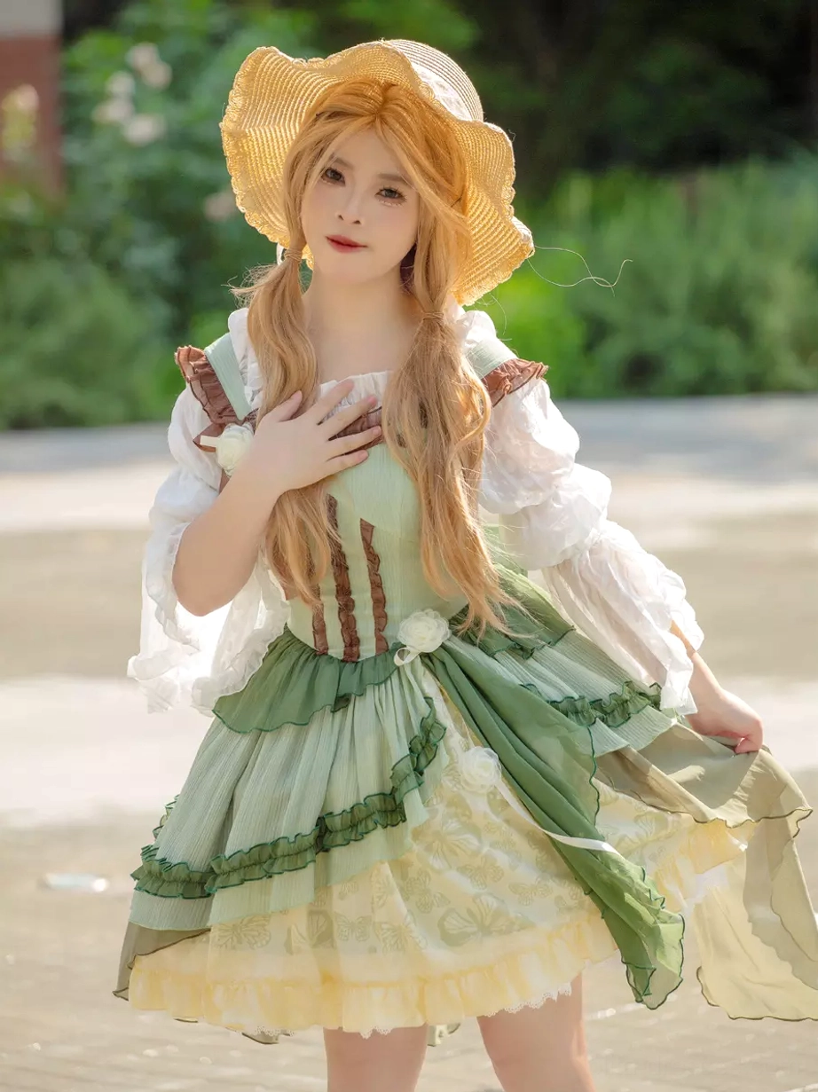 Sweet lolita JSK medium shot front view with model hand placement and flowing green skirt fabric in paved outdoor garden setting