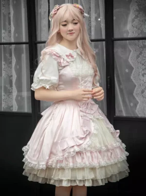 Pink and white sweet lolita jumper dress JSK front three-quarter view with ruffled lace hem and bow decorations on pink wig model
