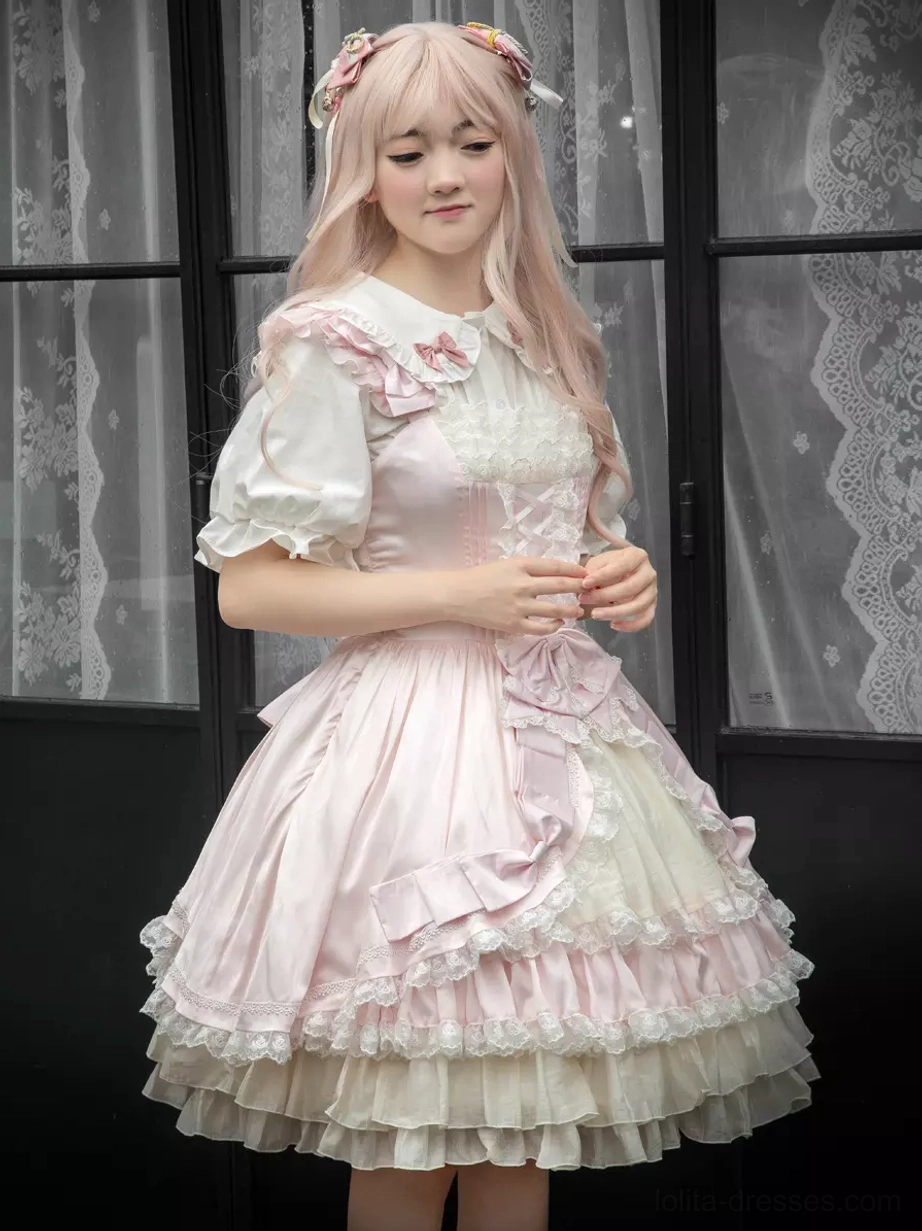 Pink and white sweet lolita jumper dress JSK front three-quarter view with ruffled lace hem and bow decorations on pink wig model