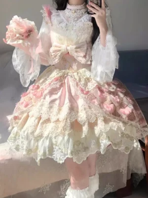 Sweet Lolita jumper skirt in soft pink with layered lace hem, front view with detachable puff sleeves and decorative bow, indoor sofa setting