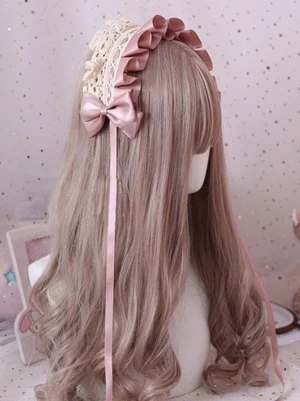 Sweet Lolita lace bow headband with blush pink satin bow and beige crochet lace, worn on mannequin with long curly wig showing right rear wearing view with extended pink ribbon tail