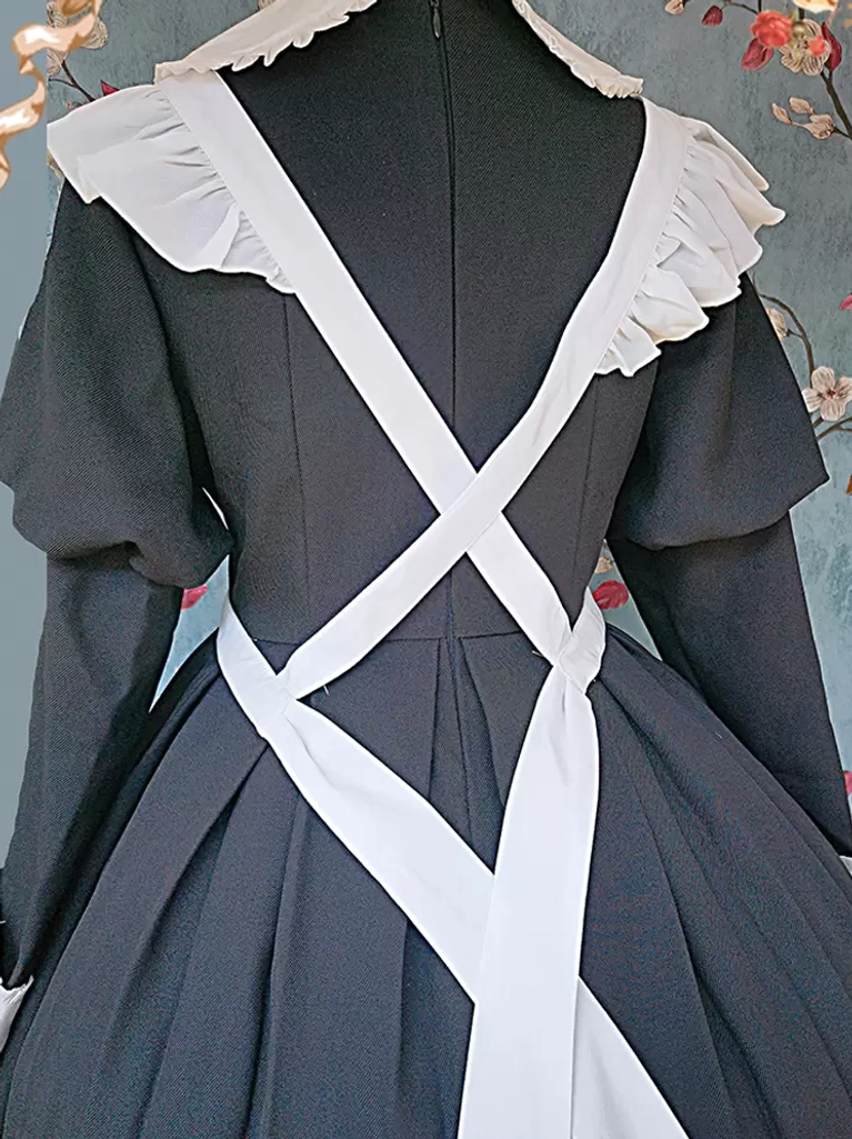 Sweet lolita maid apron back view showing cross-shaped white apron straps and pleated skirt construction indoor background