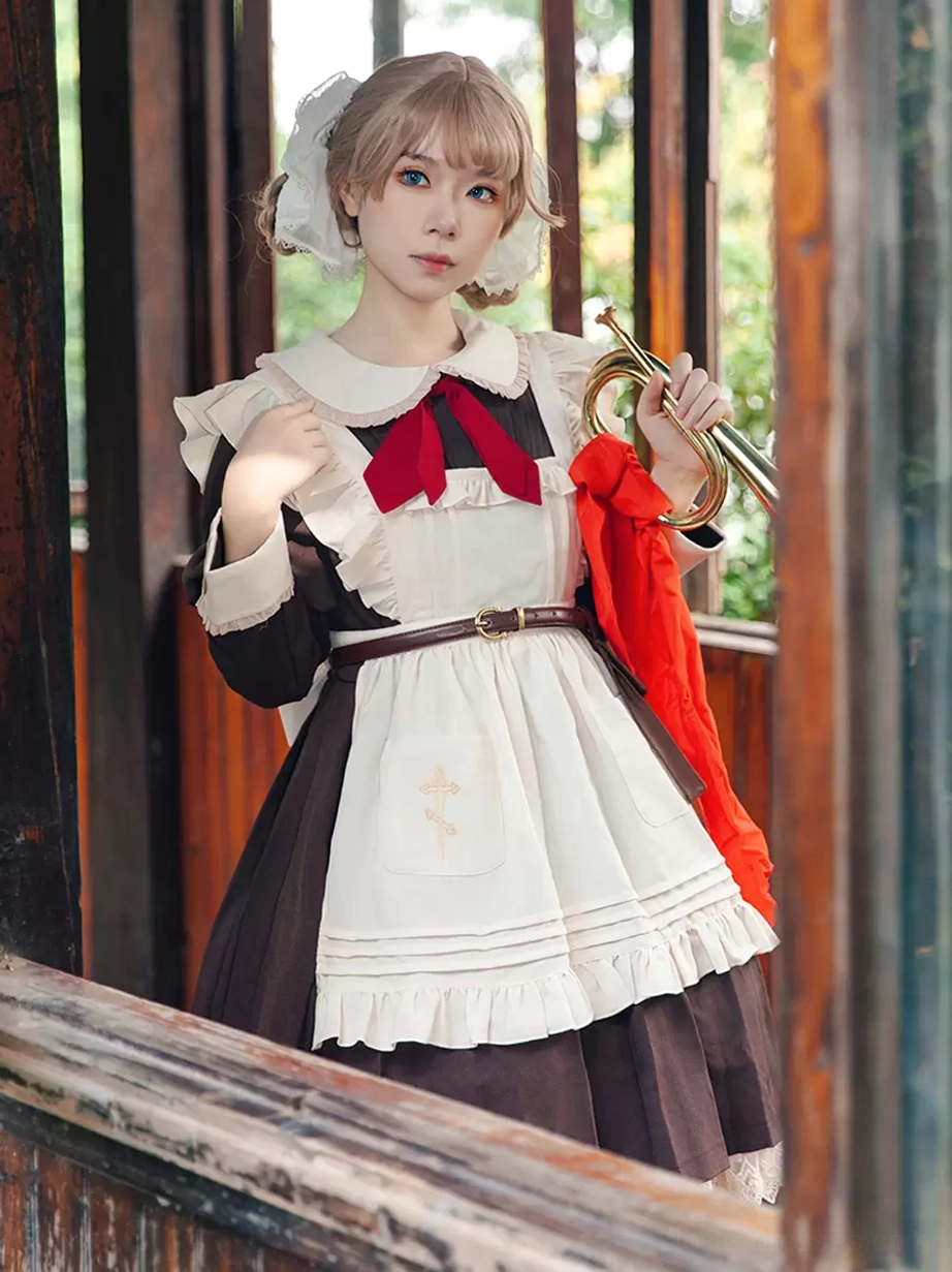 Sweet lolita maid apron front view worn by cosplayer in indoor window room with brown-black color scheme hair accessories