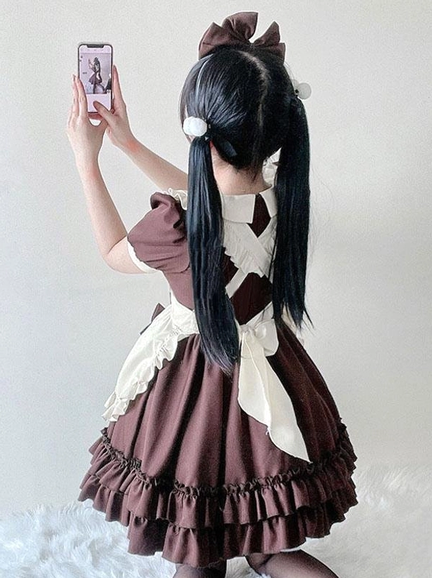 Back view of Sweet Lolita maid dress featuring dark brown main body, beige apron accent, tiered ruffled skirt layers, and large hair bow