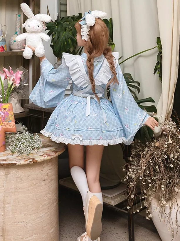 Back full view of light blue gingham lolita maid dress displaying ruffled skirt hemline braided hair with flower hairpin and layered ruffle details from rear angle