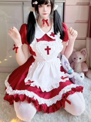 Full front kneeling pose of nurse-themed sweet lolita dress featuring heart-shaped apron with cross, red bow tie, white stockings, and voluminous ruffled skirt hem detail