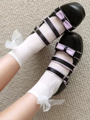 Top-down close-up of sweet lolita shoes featuring heart-shaped buckle and bow details with knitted fabric background