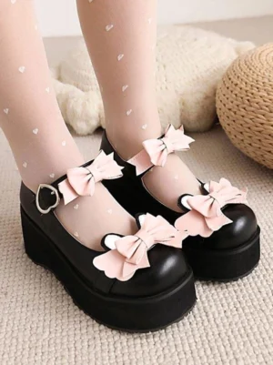 Black Sweet Lolita Mary Jane platform shoes with pink dual bows, close-up overhead view showing round toe and decorative bow embellishments paired with heart-patterned stockings