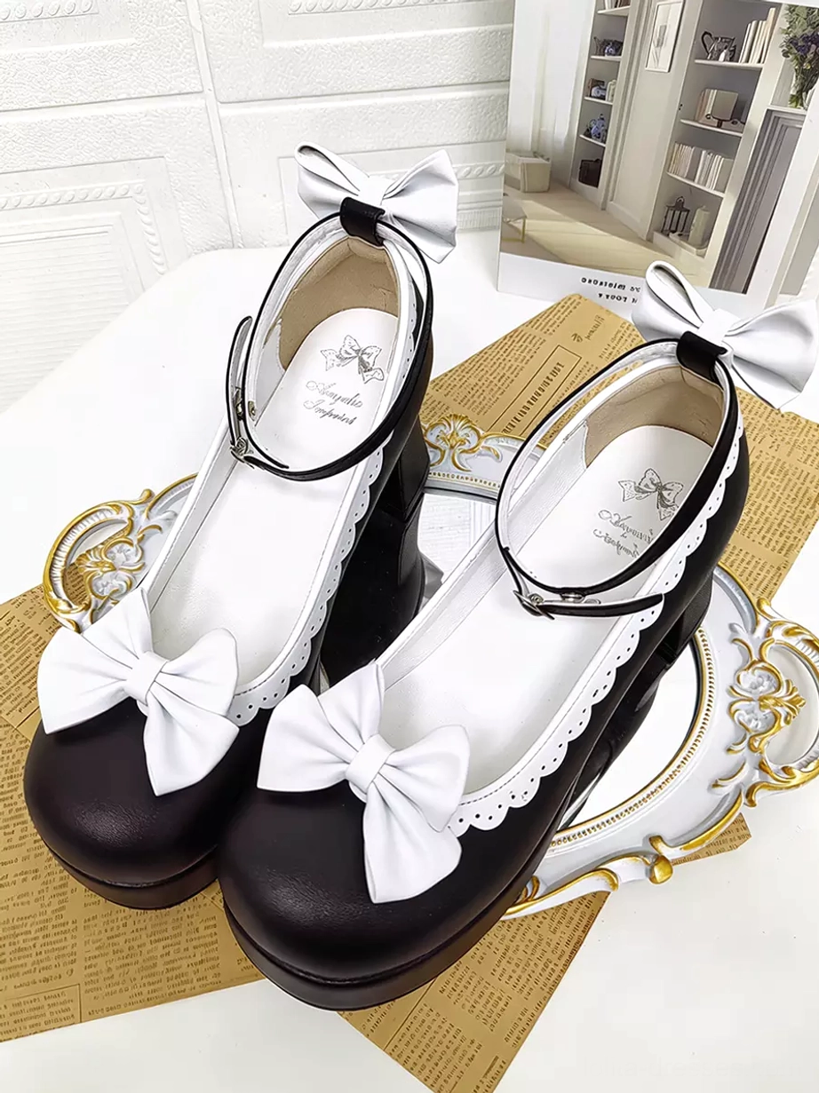 Pair of Sweet Lolita Mary Jane pumps with large white front bows, scalloped lace trim, thick block heels, branded insoles visible, displayed on decorative tray tabletop scene